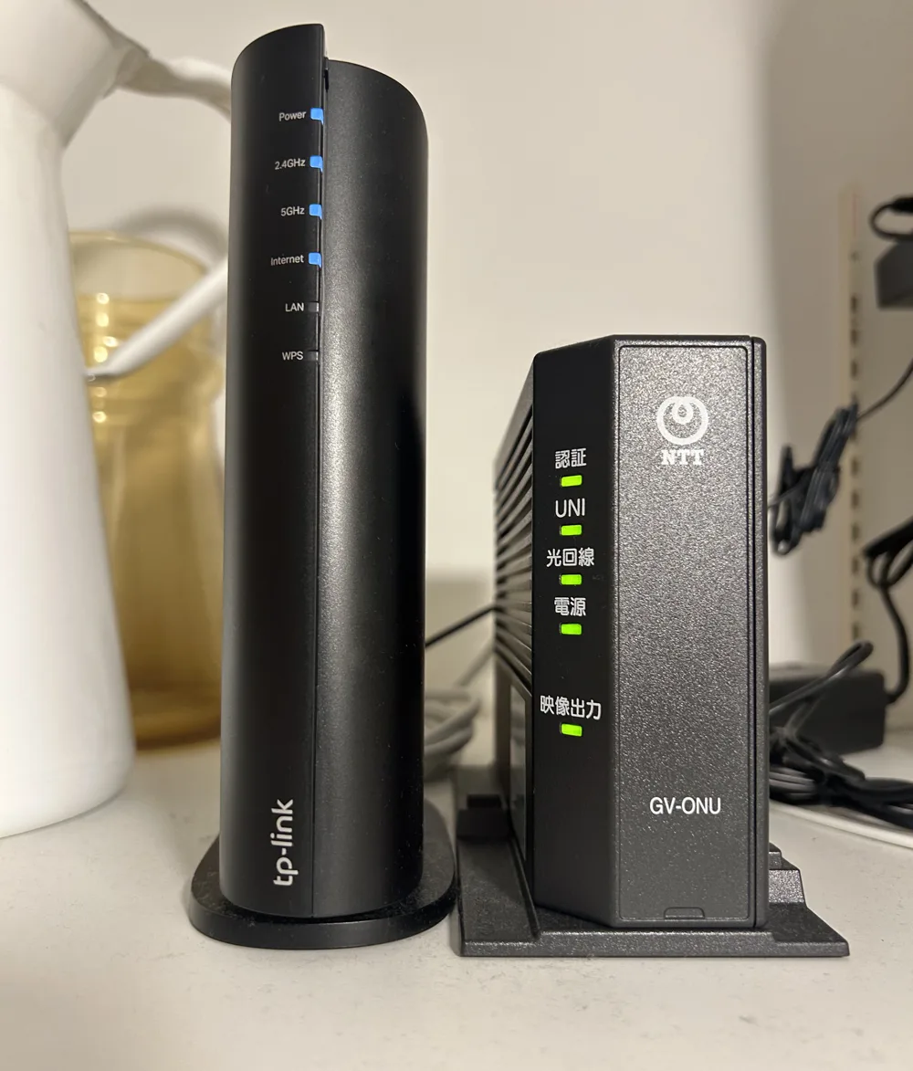 TP-LinkのWi-FiルーターArcher AX3000（左）とNTTのONU（右）を棚に並べて置いた様子
